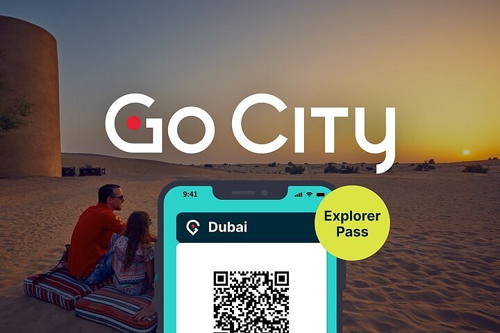 Famiglia seduta nel deserto al tramonto con un cellulare su cui è esposto un "pass Go City Explorer" per Dubai.