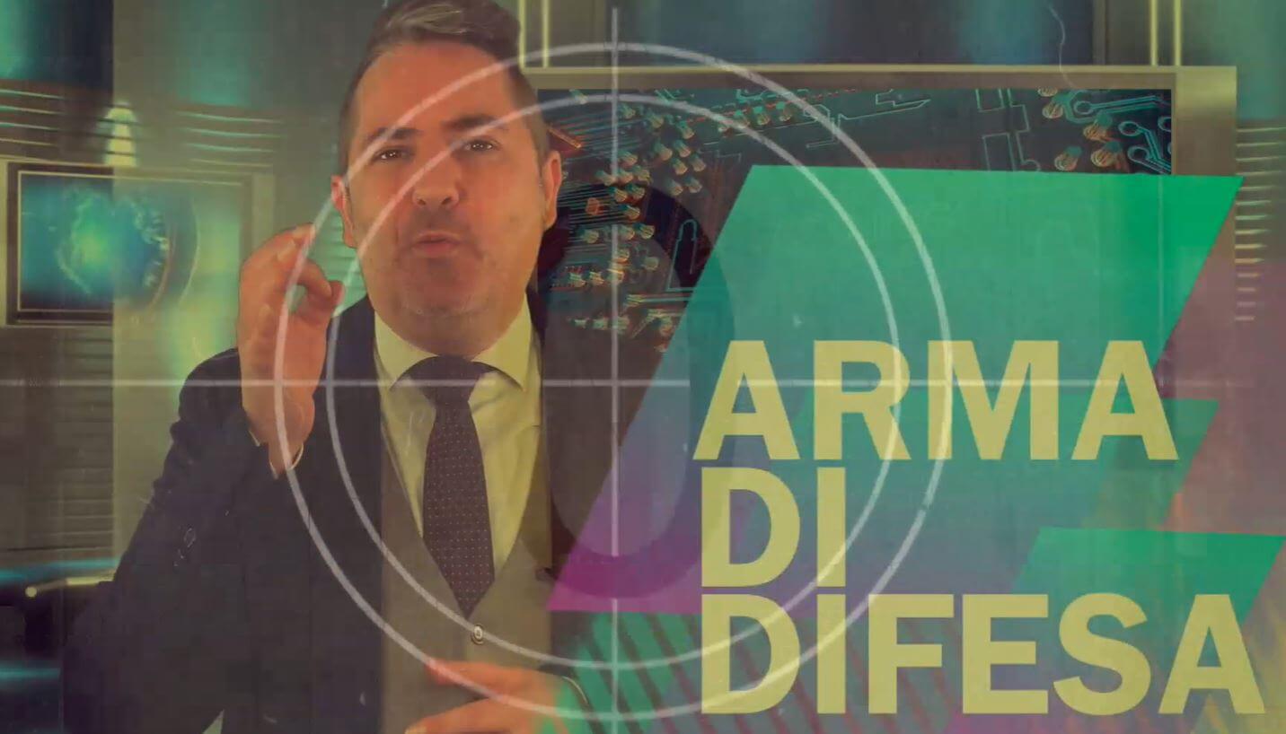 Uomo che gesticola mentre si presenta con le parole "arma di difesa" ben visibili in primo piano.